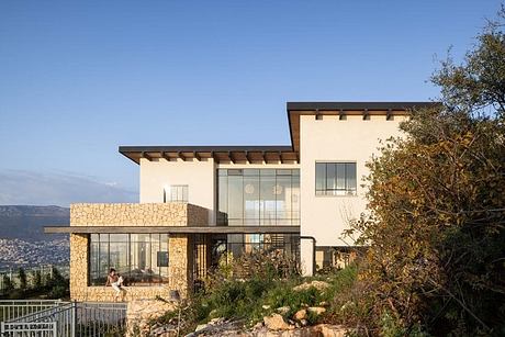 Stylish hillside home with stone facade, large glass windows, and wooden accents.