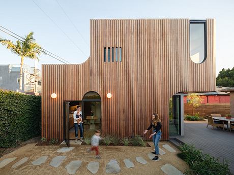 Wooden siding, curved entryway, and outdoor seating area in modern residential design.