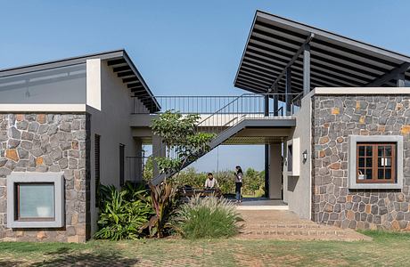 Stunning stone and wood architectural design with balcony and lush greenery.