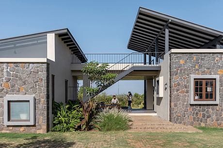 Stunning stone and wood architectural design with balcony and lush greenery.