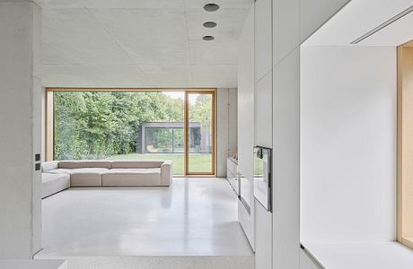 Bright, minimalist living space with large windows overlooking lush greenery.