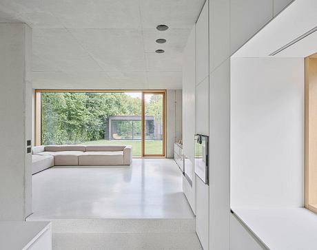 Bright, minimalist living space with large windows overlooking lush greenery.