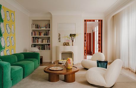 A cozy, modern living room with a green sofa, wooden coffee table, and built-in bookshelf.