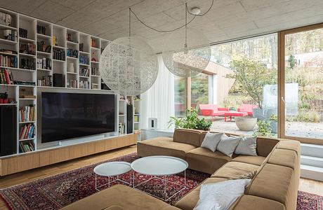 Spacious living room with built-in bookshelves, concrete ceiling, and large windows.