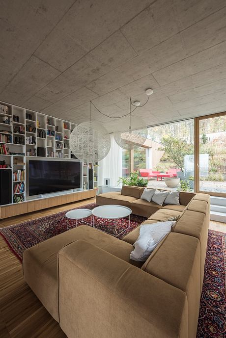 Spacious living room with built-in bookshelves, concrete ceiling, and large windows.