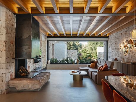 Rustic wood-beamed ceiling, stone walls, and sleek modern furniture create a cozy ambiance.