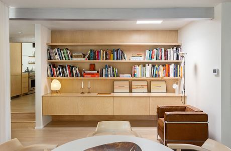 Spacious living room with built-in bookshelves, wooden furniture, and warm lighting.