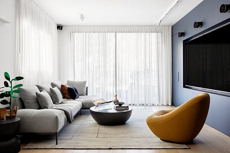 Minimalist living room with large sectional sofa, yellow armchair, and sleek coffee table.