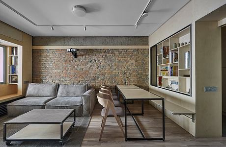 Living room with exposed brick wall, industrial furnishings, shelving, and desk space.