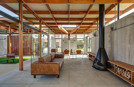 Open-concept living space with exposed wooden beams, concrete floors, and a cozy fireplace.