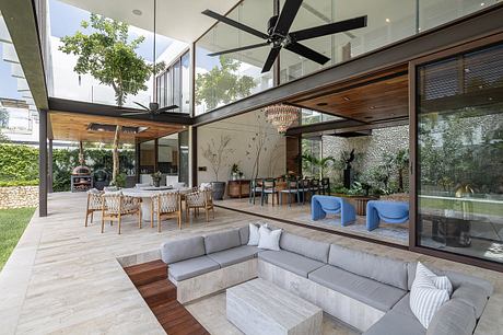 Contemporary open-plan living space with wooden beams, large windows, and outdoor patio.