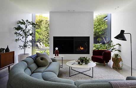 Modern, minimalist living room with sleek fireplace, plush seating, and lush greenery.