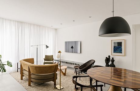 Modern, minimalist living space with wooden furniture, pendant lighting, and abstract artwork.