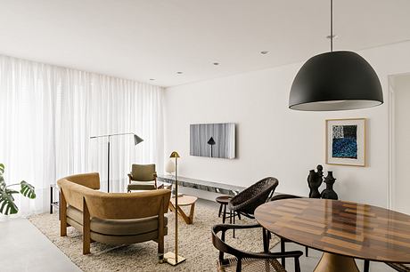 Modern, minimalist living space with wooden furniture, pendant lighting, and abstract artwork.