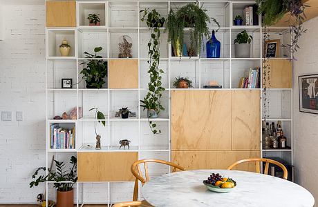 Minimalist living space with modular shelving, marble table, and natural wood furnishings.