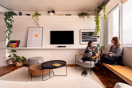 Cozy modern living room with sleek furniture, artwork, and lush greenery accents.