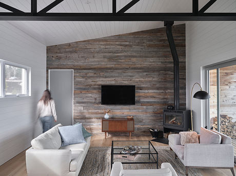Cozy cabin living room with rustic wood paneling, fireplace, and modern furnishings.