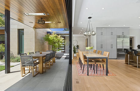 A modern open-plan kitchen and dining area with sleek wood and stone finishes.