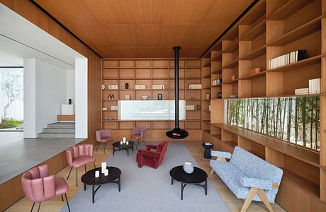 A cozy and modern living space with a wood-paneled ceiling, built-in shelving, and vibrant seating.