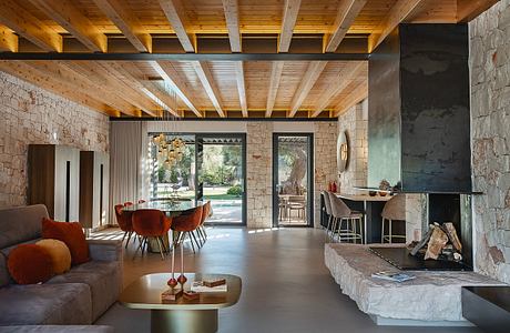 A cozy, rustic living space with exposed wooden beams, stone walls, and a modern fireplace.