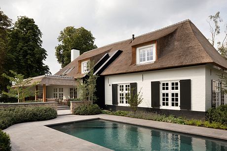 Charming thatched-roof home with a patio, pool, and traditional design elements.