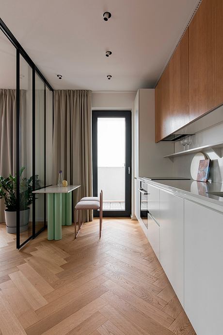 Minimalist kitchen space with wooden cabinets, curtains, and herringbone hardwood floors.