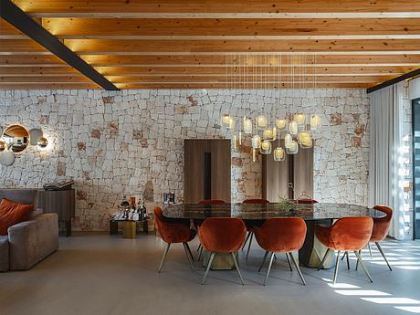 Rustic dining room with stone feature wall, wooden ceiling beams, and modern pendant lights.