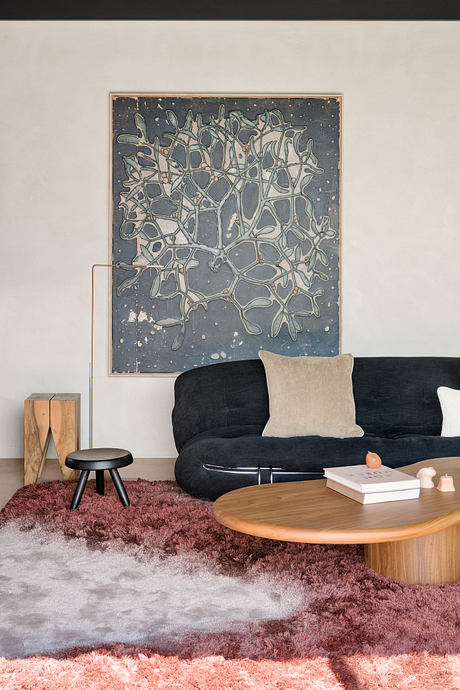 Sleek modern living room with abstract artwork, plush rug, and natural wood accents.