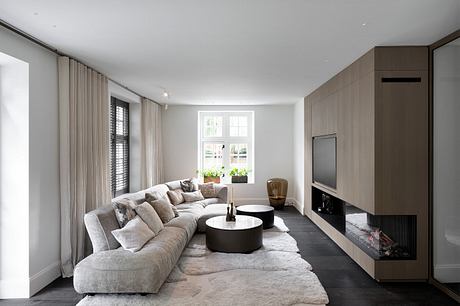 Spacious, modern living room with large sectional sofa, round coffee tables, and fireplace.