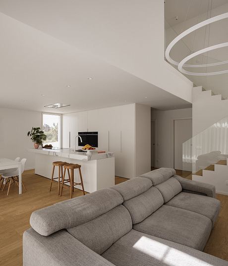 Spacious open-concept living area with modern, minimalist kitchen and curved staircase.