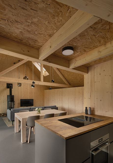 Rustic wooden beams, modern kitchen with black countertop, minimal decor, cozy living space.