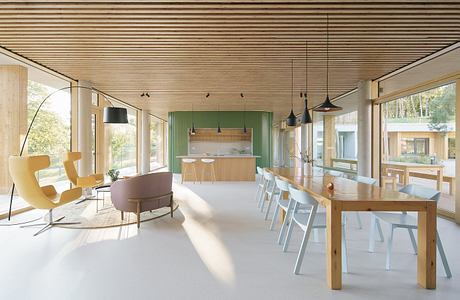 Modern open-plan interior with wood panels, minimalist furniture, and natural lighting.