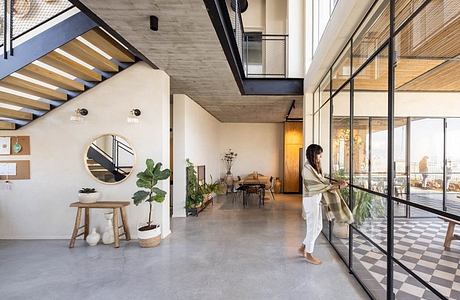 Modern loft-style interior with concrete walls, wooden stairs, and large windows.