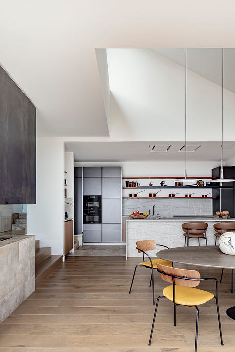 Sleek, modern kitchen with gray cabinets, open shelves, and a round wood dining table.