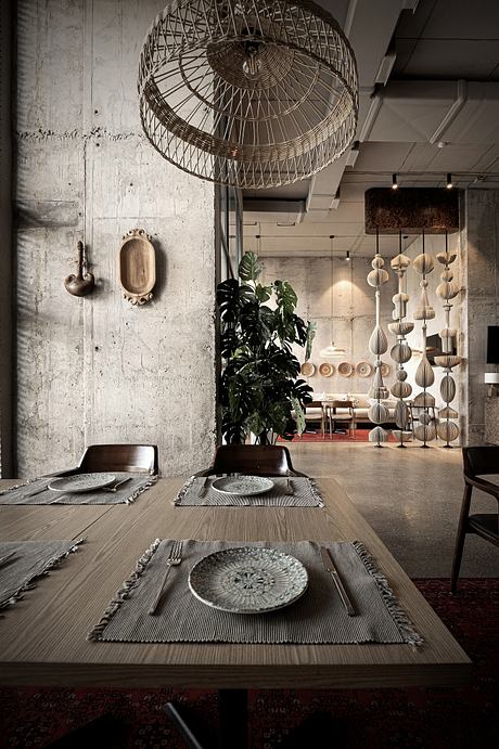 A rustic, industrial-chic dining space with woven light fixtures, plants, and textured tableware.