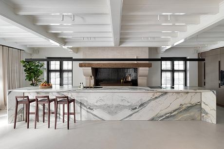 Spacious kitchen with modern marble countertop, wood-beam ceiling, and industrial lighting.