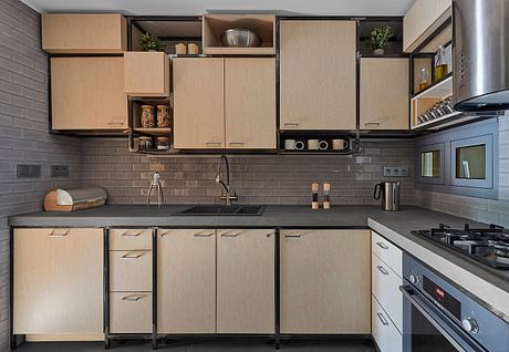 Modern kitchen with wood-toned cabinetry, sleek appliances, and textured backsplash.