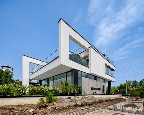 Modern, angular architectural design with glass elements, terraces, and lush greenery.