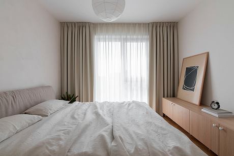 Cozy bedroom with plush bedding, minimalist furniture, and textured curtains.