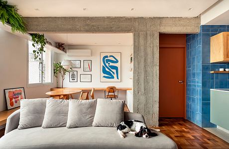 Loft-style apartment with concrete beams, modern art, and colorful tile kitchen.