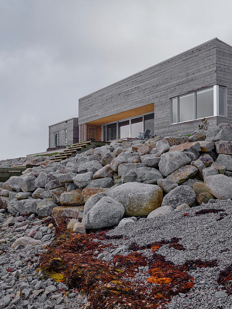 Striking modern house perched atop a rocky outcrop, with natural materials and sleek lines.
