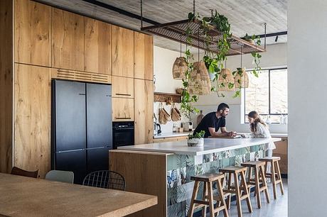 Rustic kitchen with wood paneling, hanging lights, and colorful island decor.
