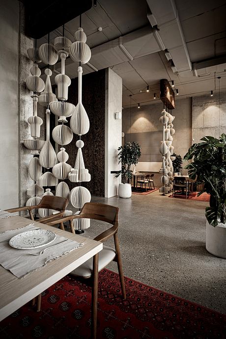 An ornate arrangement of white paper lanterns adorns the ceiling, creating a unique and captivating ambiance in this modern interior space.