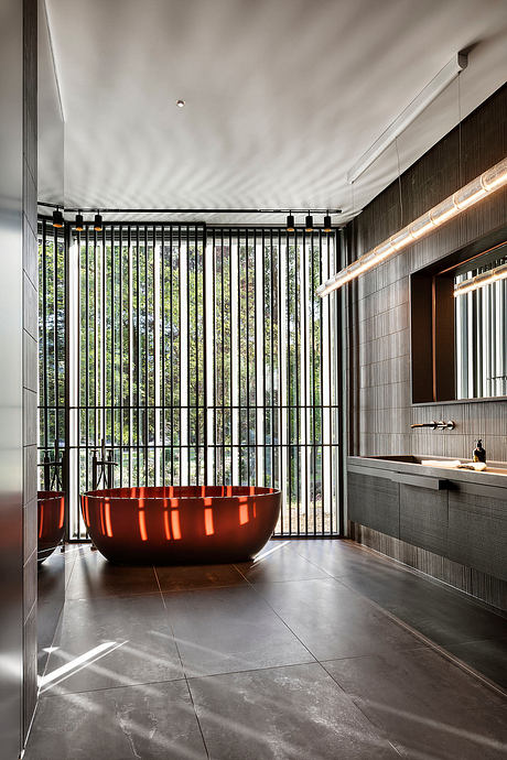 Sleek modern bathroom with a bold crimson tub, minimalist vanity, and floor-to-ceiling glass windows.