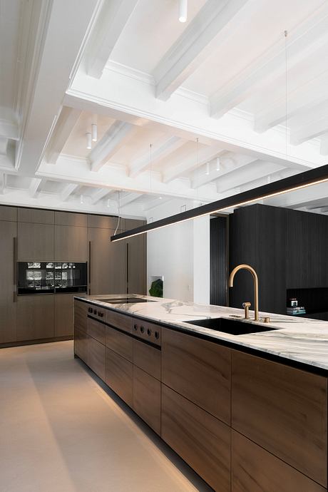 A modern kitchen with sleek cabinetry, marble countertops, and a linear pendant lighting design.