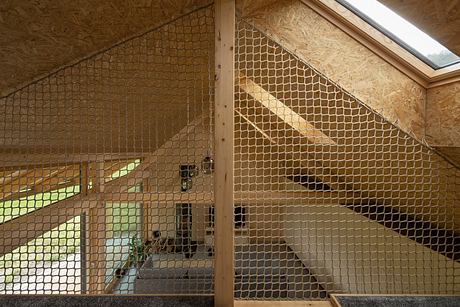 A wooden interior with an intricate net dividing the space in an architectural manner.