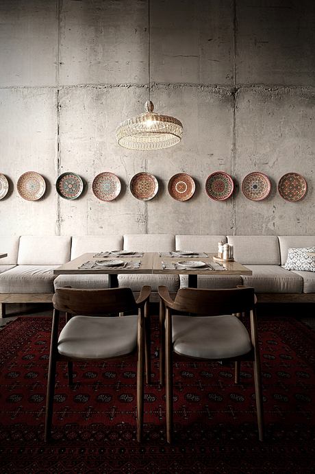 A rustic dining area with a woven pendant light, ornate wall plates, and textured seating.