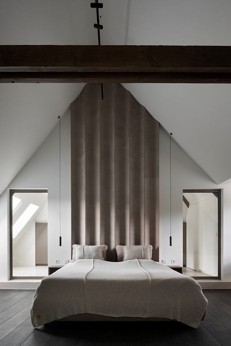 A modern bedroom with a large, pleated fabric headboard and minimalist design elements.