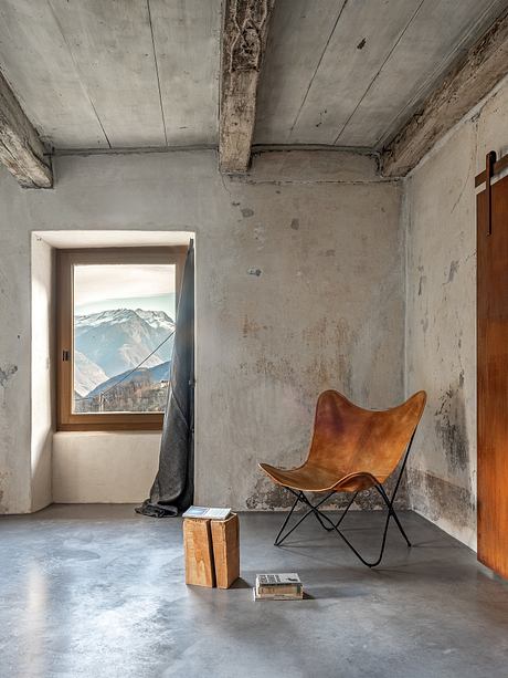 Rustic room with wooden furniture, exposed beams, and breathtaking mountain view through window.