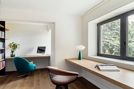 Spacious home office with floor-to-ceiling windows, wooden desk, and modern furniture.
